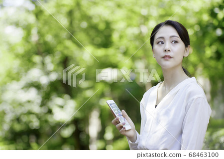 看智能手機的少婦反對新鮮的綠樹 看智能手機的少婦反對新鮮的綠樹 68463100