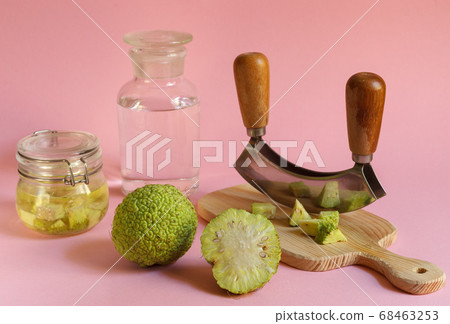 Osage green Apple and a blackboard with sliced fruit for the manufacture of medicinal tinctures. Horizontally on a pink background 68463253