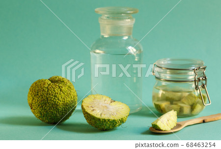 Green fruit osage orange, jar with tincture on a green background, horizontally with space 68463254