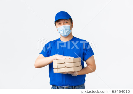 Contactless delivery, covid-19 shipping, preventing virus concept. Smiling friendly asian male courier in medical mask, gloves and blue uniform bring pizza order to client house, white background Contactless delivery, covid-19 shipping, preventing virus concept. Smiling friendly asian male courier in medical mask, gloves and blue uniform bring pizza order to client house, white background 68464010