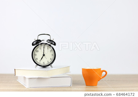 alarm clock with books and coffee cup on wooden desk and white background alarm clock with books and coffee cup on wooden desk and white background 68464172