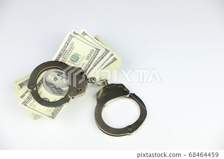 metal handcuff on 100 dollars banknote stacking on white background metal handcuff on 100 dollars banknote stacking on white background 68464459