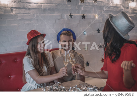 Smiling friends clinking their glasses of champagne Smiling friends clinking their glasses of champagne 68469598