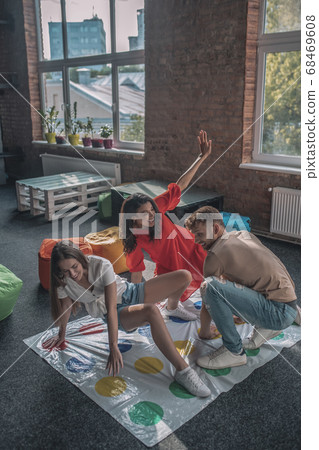Three friends playing active twister game at the party Three friends playing active twister game at the party 68469608