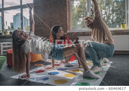 Three people having fun while playing twister game 68469617