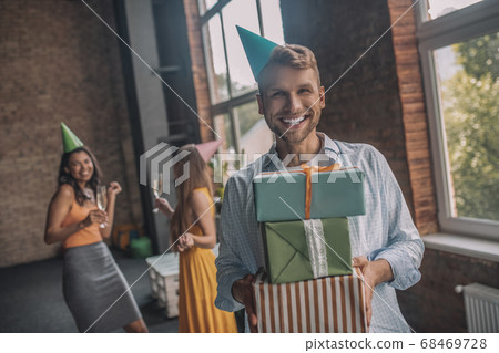 Smiling man holding a pile of his gift boxes 68469728