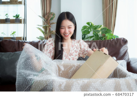 Asian woman unpack packaging after online shopping Asian woman unpack packaging after online shopping 68470317