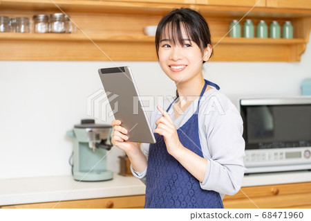 Young woman using a tablet in the kitchen Young woman using a tablet in the kitchen 68471960