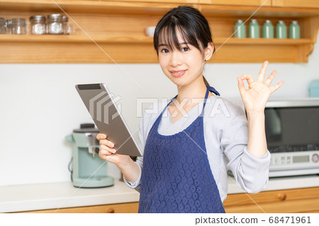 Young woman using a tablet in the kitchen Young woman using a tablet in the kitchen 68471961