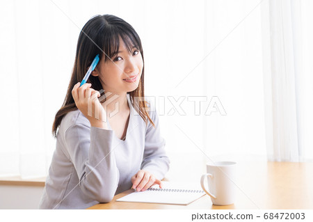 年輕女子在房間裡的筆記本上寫筆記 年輕女子在房間裡的筆記本上寫筆記 68472003