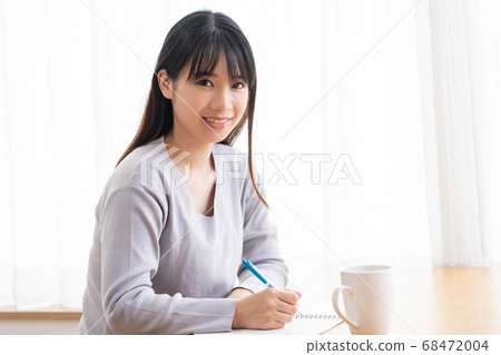 年輕女子在房間裡的筆記本上寫筆記 年輕女子在房間裡的筆記本上寫筆記 68472004