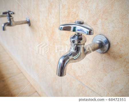 Close Up Silver Stainless Steel Faucet Hand Operated For Drinking Water In a light brown tiled tub 68472351