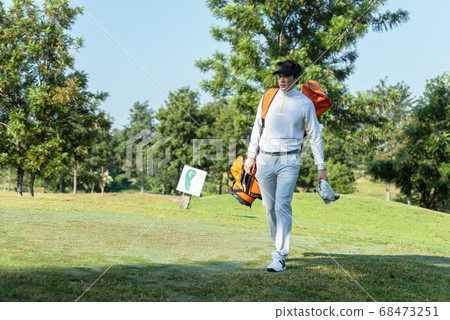 Golfer asian man walking in fairway with bag golf at golf  club.  68473251