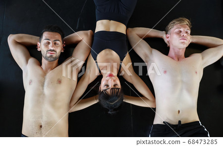 group of sporty caucasian woman and man in sport wear lying on fitness floor and resting group of sporty caucasian woman and man in sport wear lying on fitness floor and resting 68473285