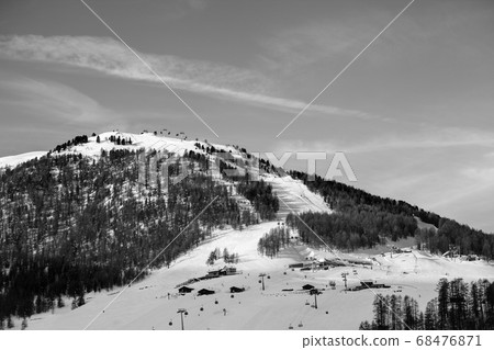Snowy ski slope with ski-lifts, traces and forest Snowy ski slope with ski-lifts, traces and forest 68476871