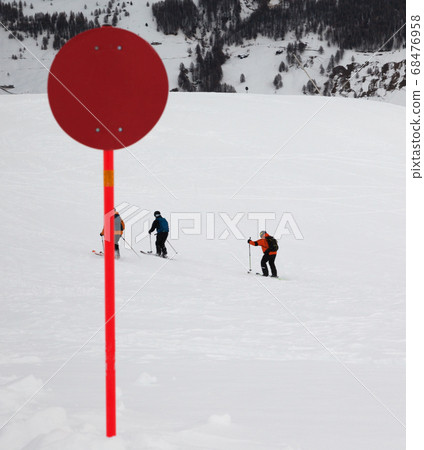 Red marker on off-piste snowy slope for freeriding Red marker on off-piste snowy slope for freeriding 68476958