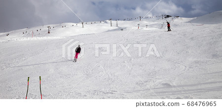 Ski poles, snowy ski slope with skiers in high Ski poles, snowy ski slope with skiers in high 68476965