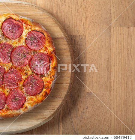 Fresh backed pizza with salami on a wooden board. Fresh backed pizza with salami on a wooden board. 68479413