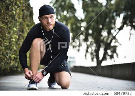 Serious bearded caucasian young sportsman tying Serious bearded caucasian young sportsman tying 68479723