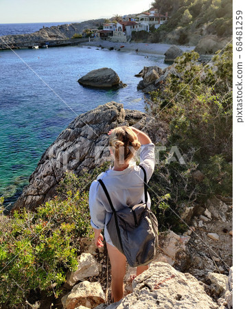 Young active feamle tourist wearing small backpack walking on coastal path among pine trees enjoing beautiful costal view of Velo Zarace beach on Hvar island, Croatia. Travel and adventure concept Young active feamle tourist wearing small backpack walking on coastal path among pine trees enjoing beautiful costal view of Velo Zarace beach on Hvar island, Croatia. Travel and adventure concept 68481259