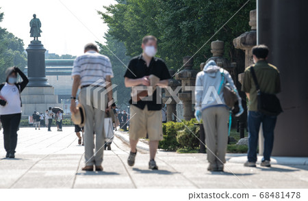 日本的東京城市風光在炎熱的白天，靖國神社在巨大的鳥居門下鞠躬的人們= 8月15日“戰爭結束” 68481478