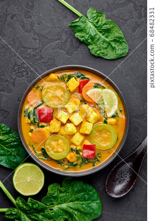 Yellow Veg Thai Curry with Tofu and vegetables in black bowl 68482331