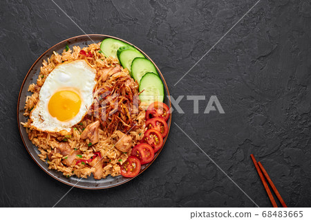 Nasi Goreng - Indonesian Chicken Fried Rice on black plate on slate table top Nasi Goreng - Indonesian Chicken Fried Rice on black plate on slate table top 68483665