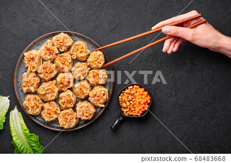 Shumai or Kanom Jeeb or Steamed Pork and Shrimp. Dumplings on a black plate on dark slate backdrop.  68483668