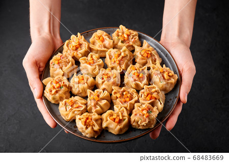 Shumai or Kanom Jeeb or Steamed Pork and Shrimp. Dumplings on a black plate on dark slate backdrop. Shumai or Kanom Jeeb or Steamed Pork and Shrimp. Dumplings on a black plate on dark slate backdrop. 68483669