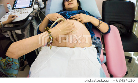 Smiling pregnant women ultrasound test with her Smiling pregnant women ultrasound test with her 68484130