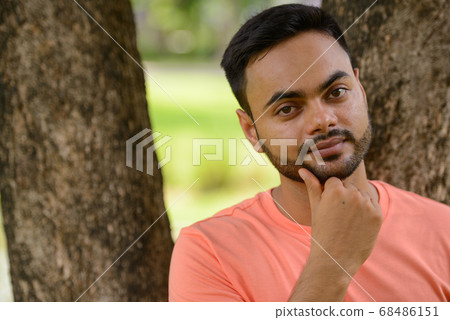 Young handsome bearded Indian man at the park Young handsome bearded Indian man at the park 68486151