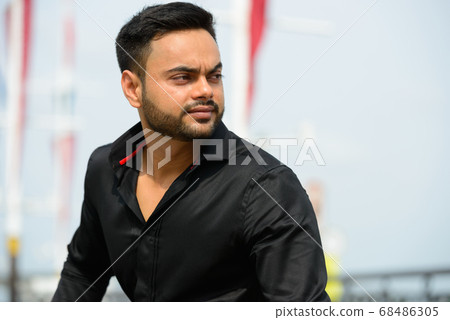Young handsome bearded Indian businessman in the city Young handsome bearded Indian businessman in the city 68486305