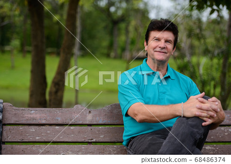 Portrait of happy mature handsome man relaxing at the park Portrait of happy mature handsome man relaxing at the park 68486374