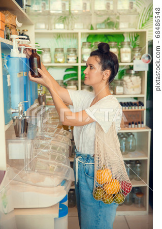 Containers with natural biodegradable household chemicals in zero waste plastic free store. Dispensers for detergents, shampoo, soap, conditioner. Sustainable alternative shopping and lifestyle 68486548