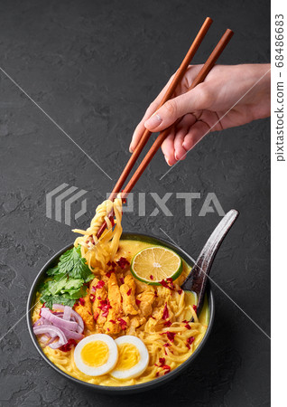 Ohn No Khao Swe in black bowl at dark slate tabl top. Myanmar Coconut Milk Noodle Soup 68486683