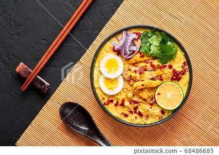 Ohn No Khao Swe in black bowl at dark slate tabl top. Myanmar Coconut Milk Noodle Soup Ohn No Khao Swe in black bowl at dark slate tabl top. Myanmar Coconut Milk Noodle Soup 68486685