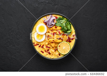 Ohn No Khao Swe in black bowl at dark slate tabl top. Myanmar Coconut Milk Noodle Soup 68486692