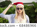 Girl in a red Christmas hat next to the swimming pool with blue water. Holiday concept. 68486966