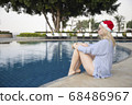 Girl in a red Christmas hat next to the swimming pool with blue water. Holiday concept. 68486967