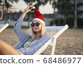 Girl in a red Christmas hat on the beach next to the sea. Holiday concept. 68486977