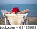 Girl in a red Christmas hat on the beach next to the sea. Holiday concept. 68486998