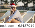 Girl in a red Christmas hat on the beach next to the sea. Holiday concept. 68487019