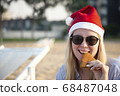 Girl in a red Christmas hat on the beach next to the sea. Holiday concept. 68487048