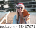 Girl in a red Christmas hat on the beach next to the sea. Holiday concept. 68487071