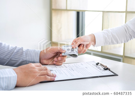 Businessman giving bribe money in the envelope of Businessman giving bribe money in the envelope of 68487335