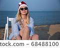 Girl in a red Christmas hat on the beach next to the sea. Holiday concept. 68488100