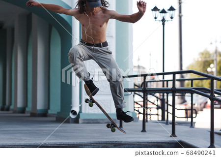 Young boy riding trick on skateboard in city 68490241