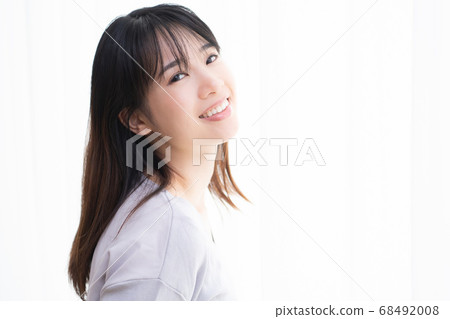 Young woman standing by the window in the room Young woman standing by the window in the room 68492008