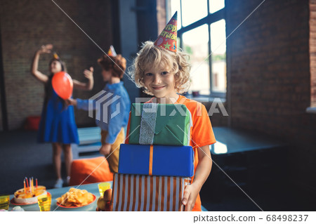 Cute blonde boy holding presents and smiling Cute blonde boy holding presents and smiling 68498237