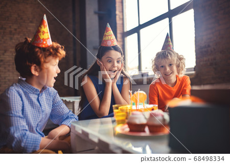 Three kids looking at the cake and looking excited Three kids looking at the cake and looking excited 68498334